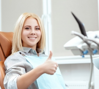 Woman in dental chair giving thumbs up