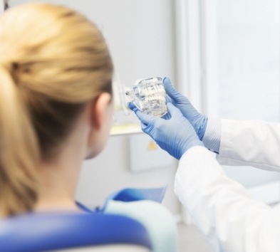 Dentist and patient looking at smile model during dental checkup and teeth cleaning visit