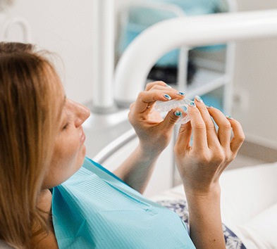 Patient holding clear aligner in treatment room