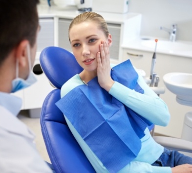 Woman in need of emergency dentistry holding cheek in pain