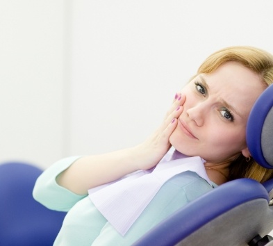 Woman in need of tooth extractions holding cheek