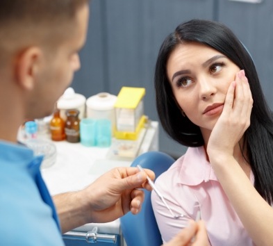 Woman in need of wisdom tooth extraction holding cheek