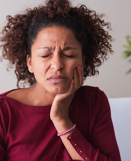 Woman in red shirt on couch with oral pain