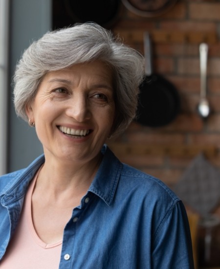 Woman with full smile after dental implant tooth replacement