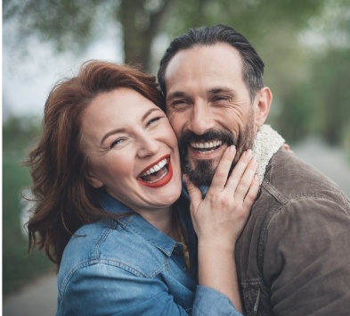 Man and woman smiling together enjoying benefits of dental implants