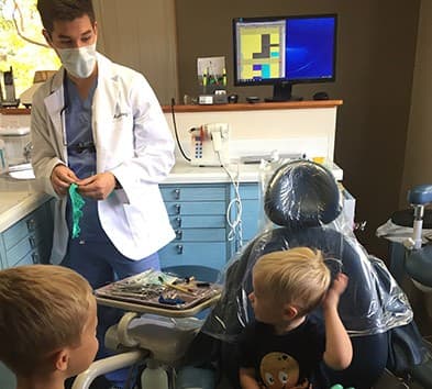 Dentist talking to young dental patients in treatment room
