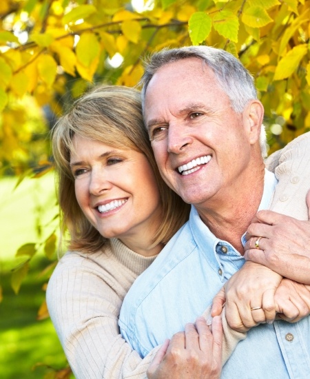 Man and woman with full smiles after replacing missing teeth