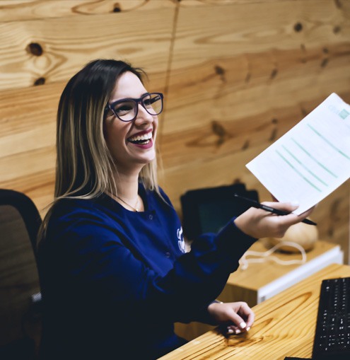 Smiling dental team member holding dental insurance forms