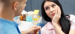 Woman in need of emergency dentistry holding cheek in pain