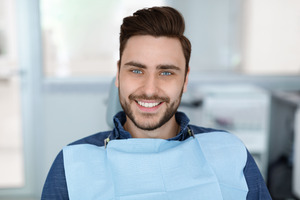 Male dental patient sitting in dental chair and smiling
