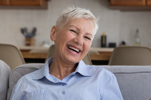 Senior woman sitting on couch and laughing