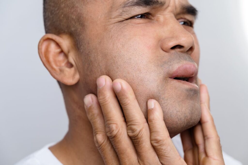 A man holding his swollen cheek